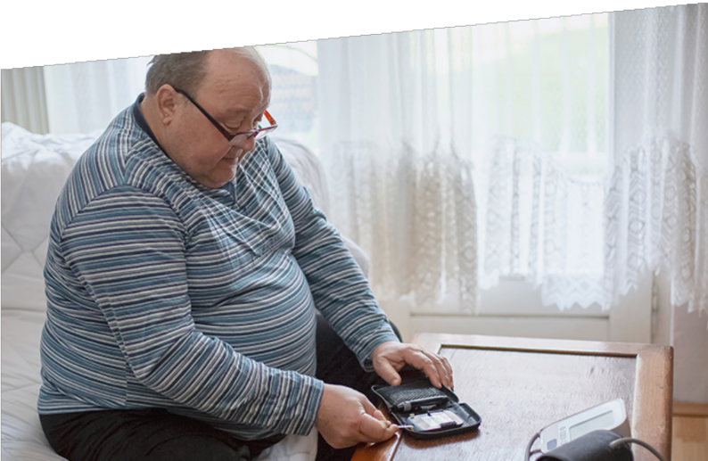 Photograph of a man an sitting down checking his blood sugar levels.