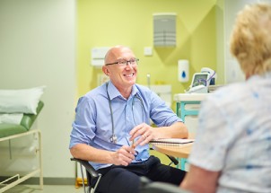 Photograph of a woman talking to a male GP.